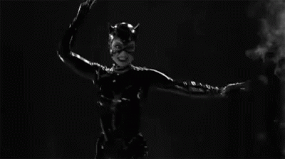 a black catwoman costume is standing in front of some smoke