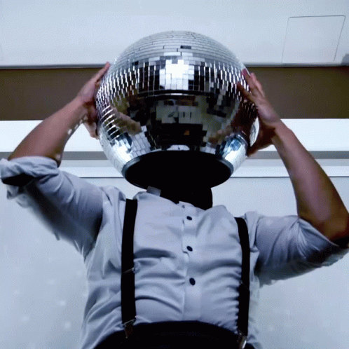 the man is holding his disco ball to his face
