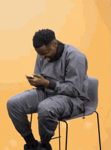 a man sitting in a chair and looking at his phone