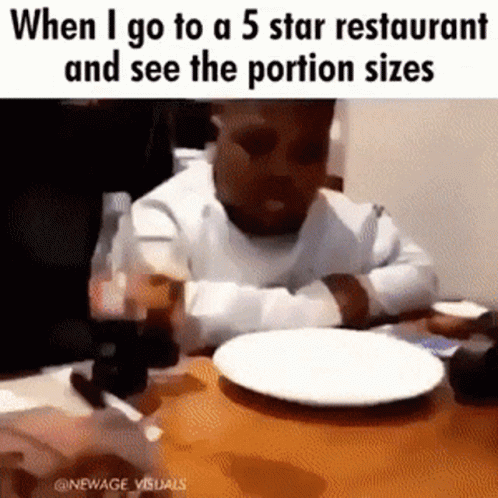 a blurry po of an infant sitting at a restaurant table with a plate
