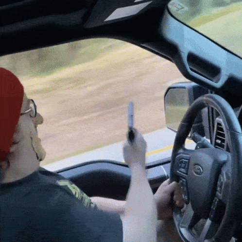 a person driving a car while holding a peace sign