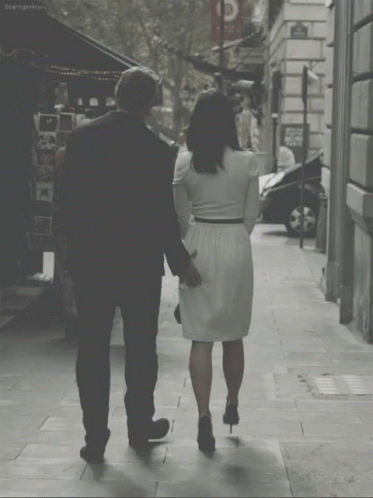 a man and woman are walking down the sidewalk together