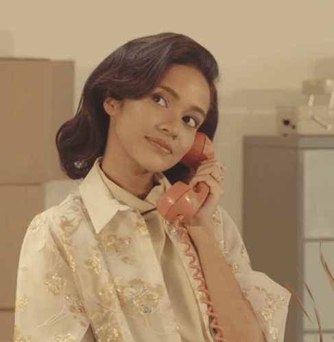 a woman is talking on the phone wearing a white shirt and tie