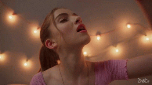 woman in a pink sweater lights around her and a ballerina necklace