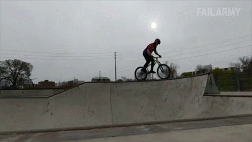 a man rides a bicycle on a ramp at dusk