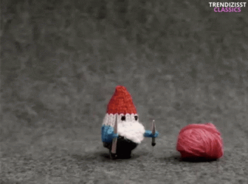a small toy bird with a knitted hat, holding a needle