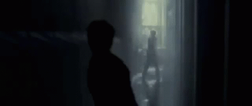 a person standing in front of a window in the dark