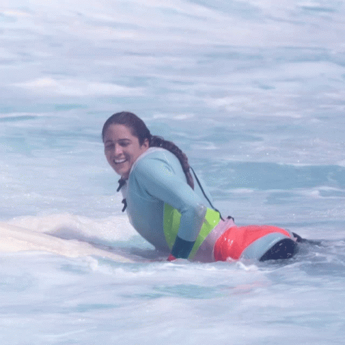 a woman laying down on a surfboard in the water