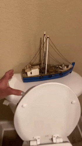 a toilet in a bathroom with a toy boat on top