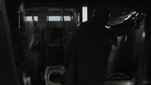 a man in a black cloak is standing inside a bus