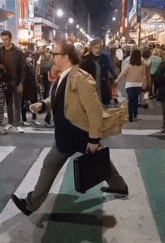 a man walks across the street with a suit case