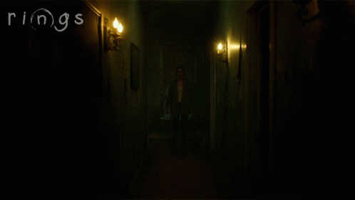 a very dark hallway with a person walking down the corridor