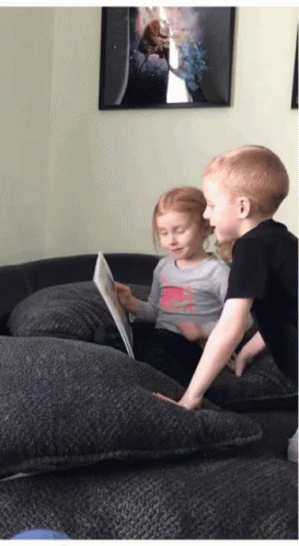 a boy and girl are looking at a book together