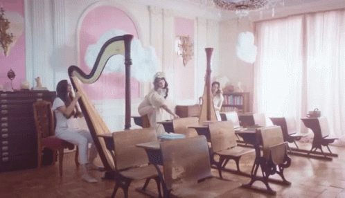 two young women play the harp for a room filled with chairs