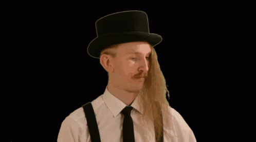 a man with long hair wearing a top hat and suspenders