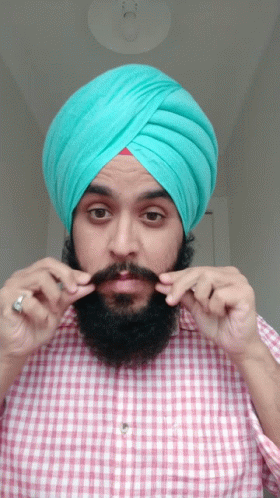 a man with beard and turban putting his fingers on his lips