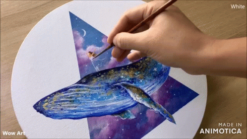 a person's hand painting on a piece of paper