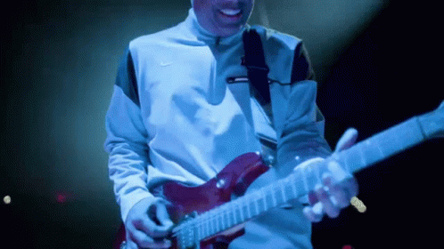 a man with a guitar smiles brightly