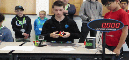 a man plays with a cube at a table with other people
