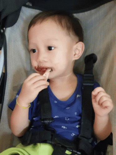 a little boy with dark blue skin brushing his teeth