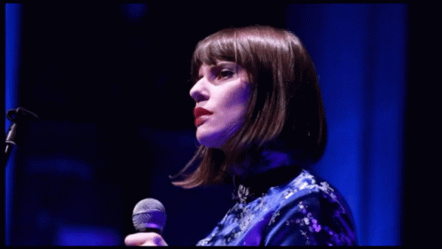 woman with dark hair and bangs in a microphone