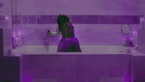 a man sitting in front of a purple tub next to mirror
