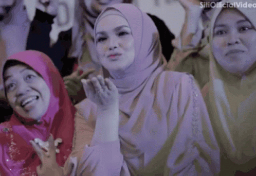 several women wearing hijabs all smiling and waving