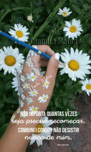 someone with a pen in their hand is touching flowers