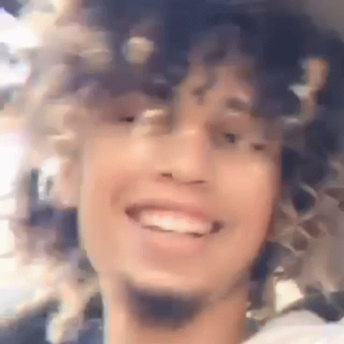 blurry pograph of a man with curly hair smiling