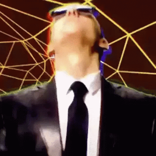 a man wearing sunglasses, a suit and tie standing in front of a large web - like structure