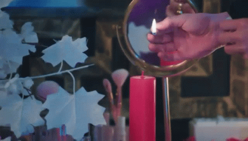 purple candle is next to a large mirror and a flower