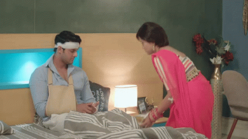 two people with blindfolds in their bedroom, one woman with an apron is in bed