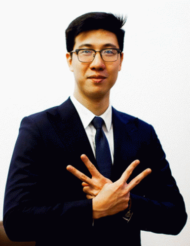 a man wearing a suit and tie, giving the hand signal