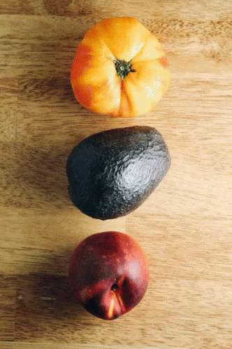 a fruit set on a wooden surface with one apple and the other an orange