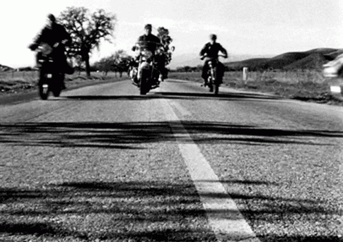 motorcycle riders are riding down the country road