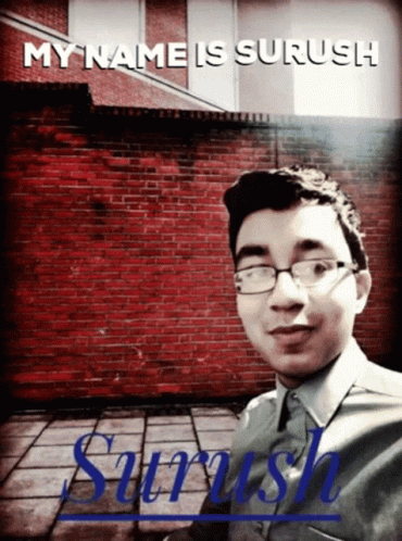 a person with glasses standing in front of a blue brick building