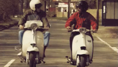 two people on motor bikes at a stop