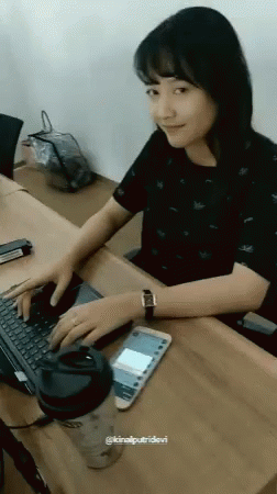 the woman is sitting at the table typing on her computer