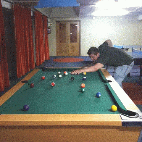 a man leaning over a green pool table