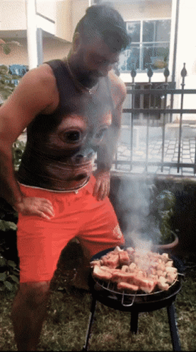a man is cooking over a barbecue in the yard
