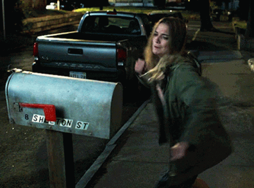 a young woman is pulling her mailbox out of the street