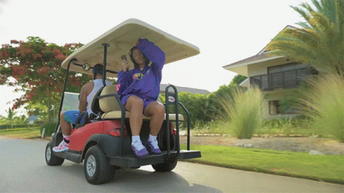 a couple of women riding in a purple golf cart