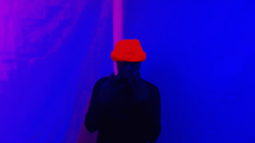 the person wearing the hat is standing in front of a red wall