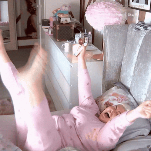 a woman in lavender pajamas lying on top of a couch