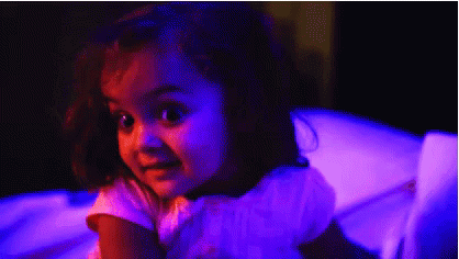 girl in dark room holding teddy bear with glowing eyes