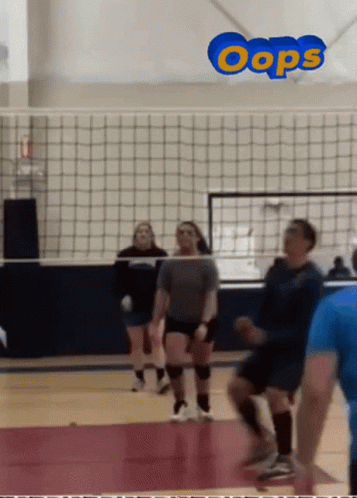 a group of people playing volleyball in a gym