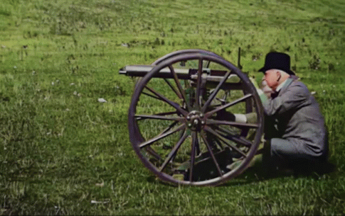 a person sitting on the ground near a wooden cannon