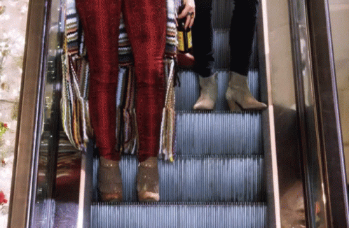 some people on an escalator one is wearing blue and the other is wearing red