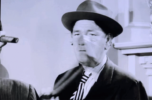 a man in a suit and hat next to another person