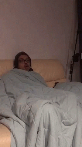 a person laying in a bed with a blanket on